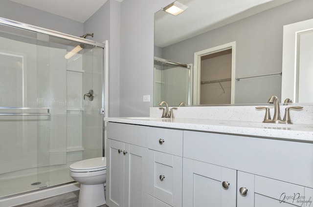 bathroom with a shower with door, vanity, hardwood / wood-style flooring, and toilet