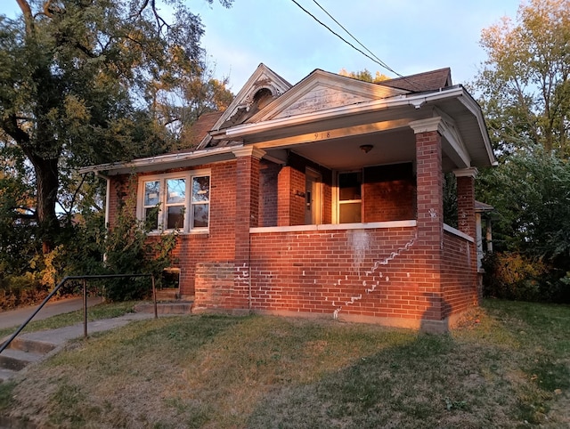 bungalow-style house featuring covered porch and a front lawn