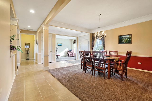 dining space with light tile patterned floors, a notable chandelier, ornamental molding, and ornate columns