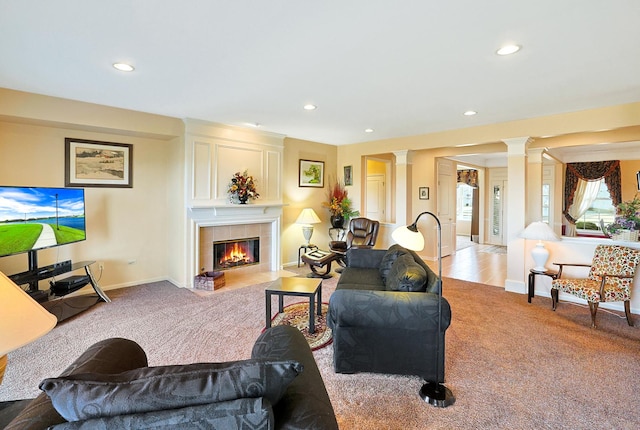 living room featuring light carpet, a tiled fireplace, and ornate columns