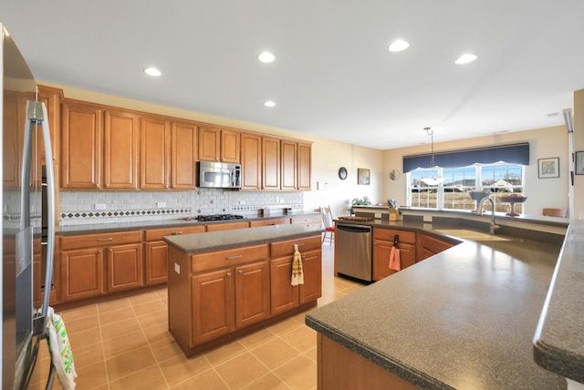 kitchen featuring a kitchen island, appliances with stainless steel finishes, pendant lighting, sink, and backsplash