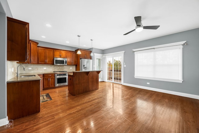 kitchen featuring a kitchen island, sink, a kitchen bar, hanging light fixtures, and stainless steel appliances