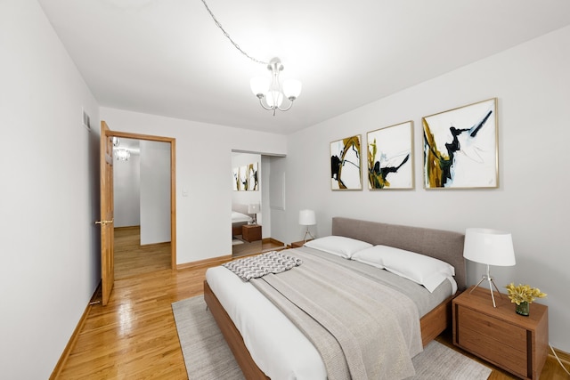 bedroom with an inviting chandelier, wood-type flooring, and a closet