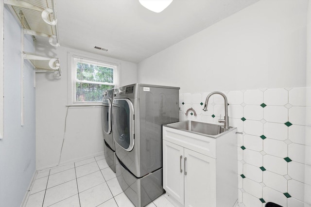 washroom featuring sink, tile walls, cabinets, washer and dryer, and light tile patterned flooring