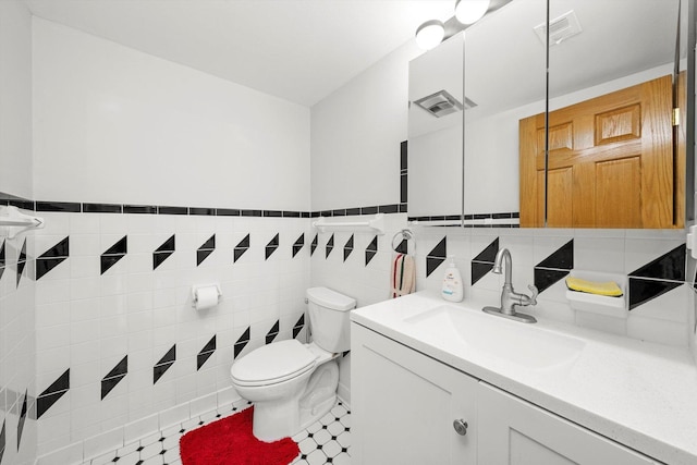 bathroom featuring vanity, tile walls, and toilet