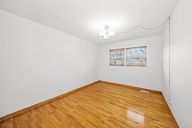 unfurnished room featuring an inviting chandelier and light wood-type flooring