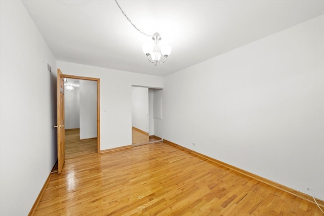 unfurnished bedroom with an inviting chandelier, hardwood / wood-style floors, and a closet