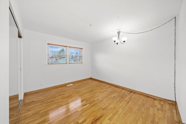 spare room with hardwood / wood-style flooring and a notable chandelier