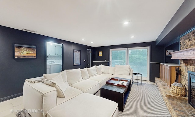 living room with a brick fireplace and separate washer and dryer