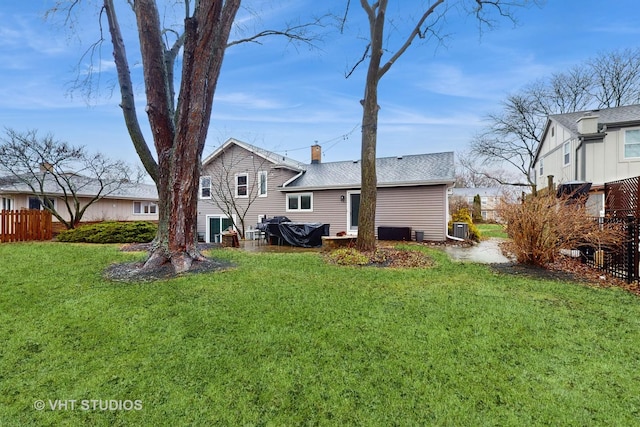 back of house with central AC unit and a lawn