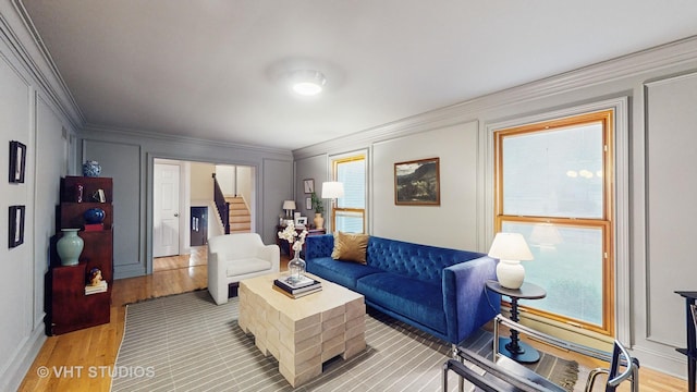 living room with light hardwood / wood-style flooring, crown molding, and a healthy amount of sunlight