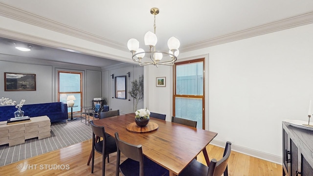 dining area with light hardwood / wood-style flooring, crown molding, and a chandelier