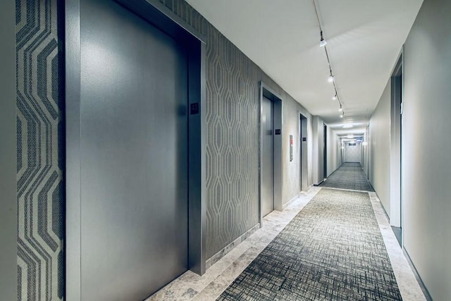 corridor featuring track lighting and elevator