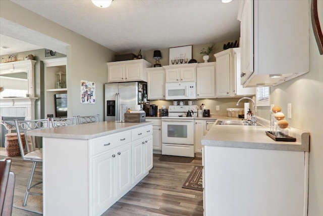 kitchen featuring white cabinetry, sink, a breakfast bar area, a center island, and white appliances