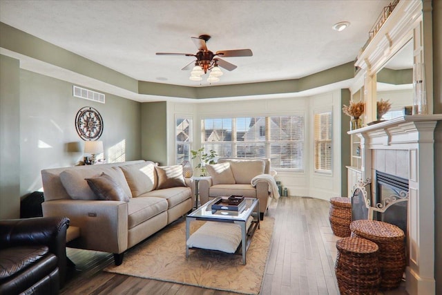 living room with ceiling fan, hardwood / wood-style floors, and a fireplace