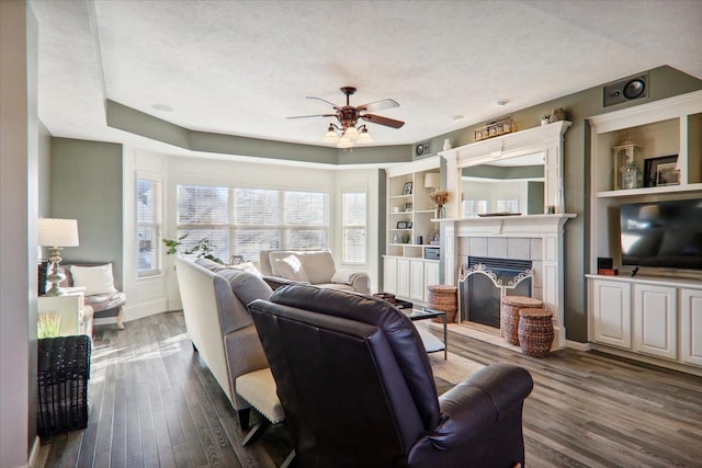 living room with a tile fireplace, dark hardwood / wood-style floors, and a textured ceiling