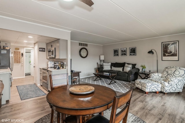 dining area with ceiling fan, a baseboard radiator, and light hardwood / wood-style floors