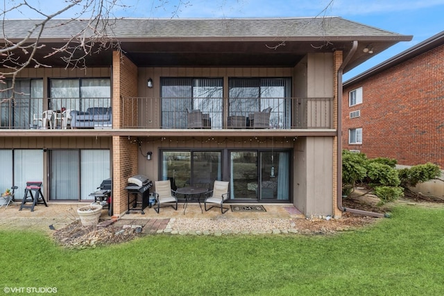 back of house featuring a yard, a balcony, and an outdoor fire pit