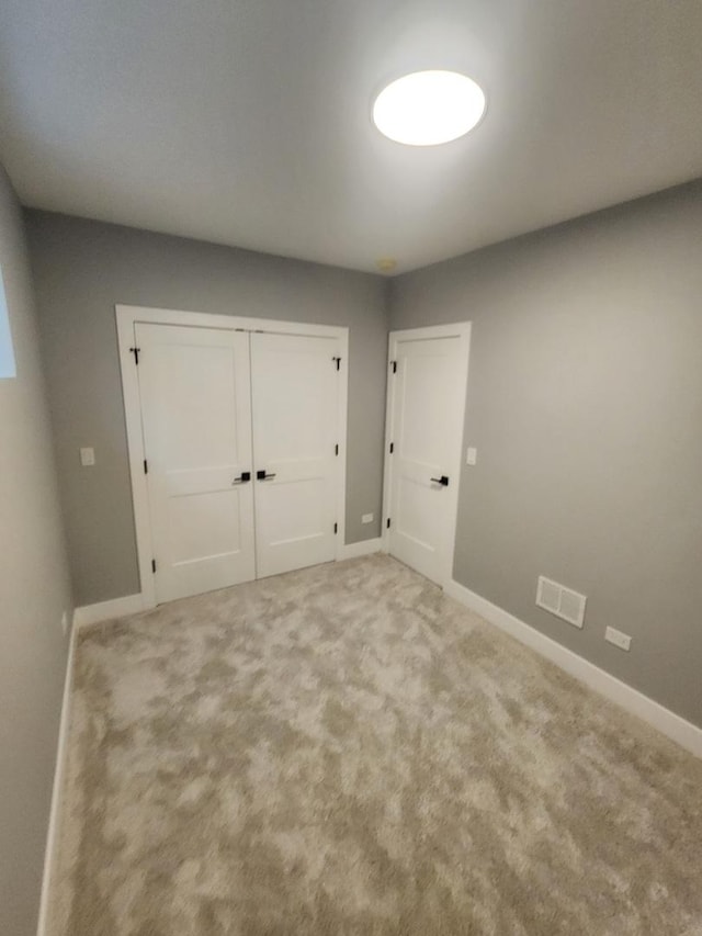 unfurnished bedroom with light colored carpet and a closet