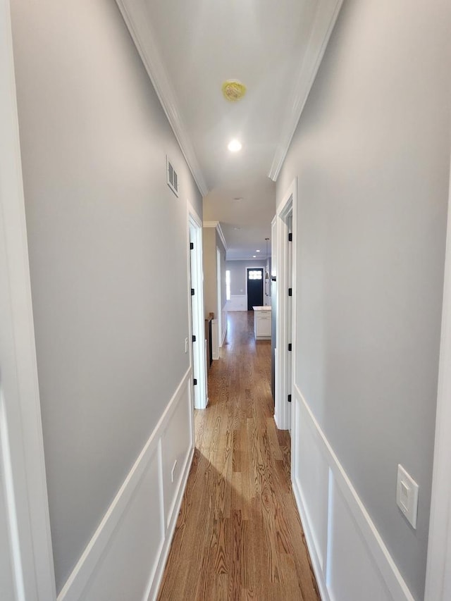 hallway with crown molding and light wood-type flooring