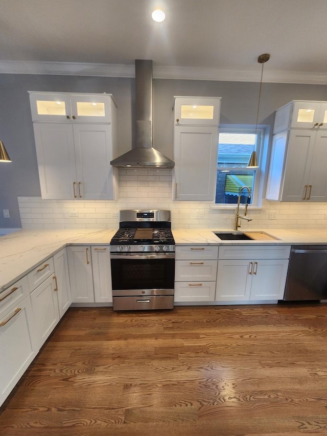 kitchen with sink, white cabinets, stainless steel appliances, crown molding, and wall chimney range hood