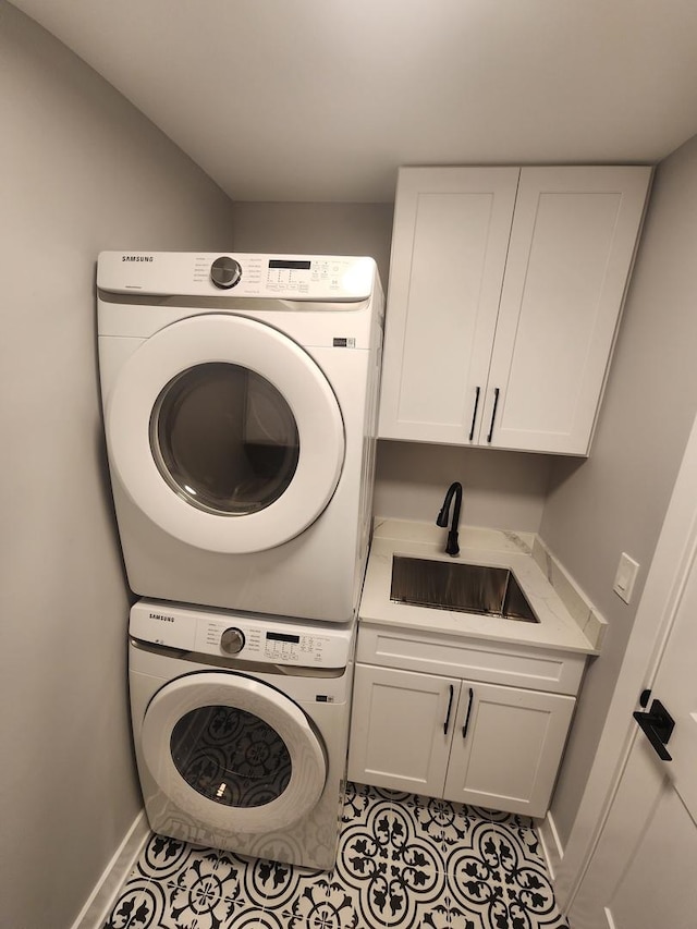 washroom with cabinets, stacked washer and dryer, light tile patterned flooring, and sink