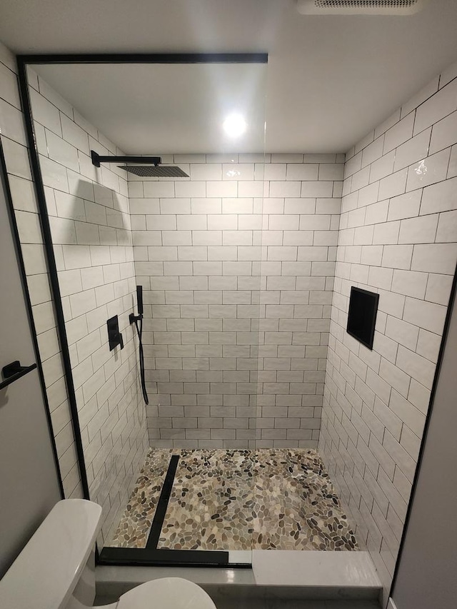 bathroom featuring toilet and a tile shower