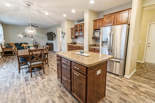 kitchen featuring hardwood / wood-style flooring, appliances with stainless steel finishes, a center island, decorative light fixtures, and a chandelier