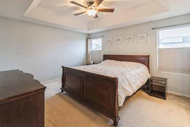 carpeted bedroom with ceiling fan and a raised ceiling