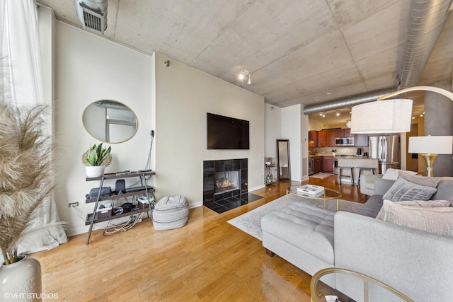 living room featuring a tiled fireplace and light hardwood / wood-style flooring