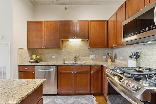 kitchen featuring light stone counters, sink, backsplash, and stainless steel appliances