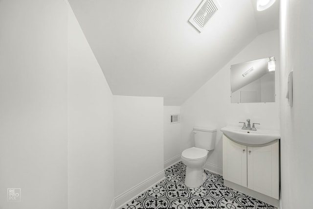 bathroom with lofted ceiling, toilet, tile patterned flooring, and vanity