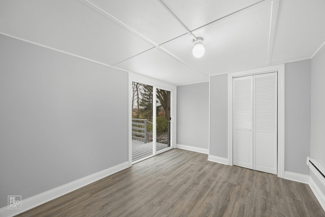 unfurnished bedroom with a baseboard radiator, access to outside, hardwood / wood-style floors, and a closet