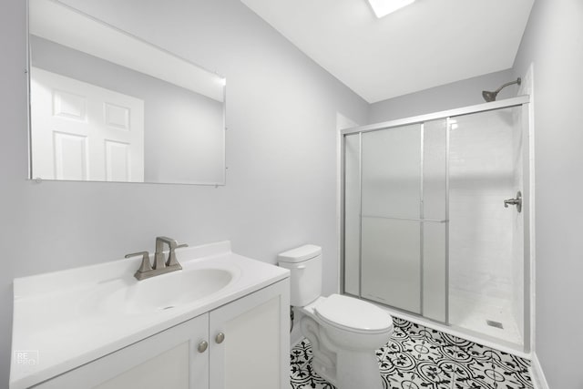 bathroom featuring a shower with door, vanity, tile patterned flooring, and toilet