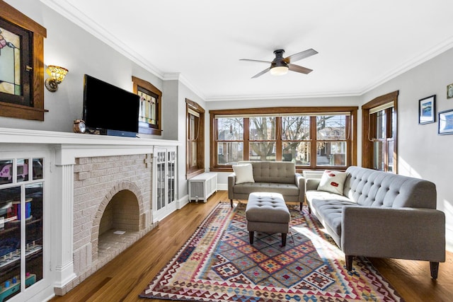 living room featuring hardwood / wood-style floors, crown molding, a fireplace, and ceiling fan