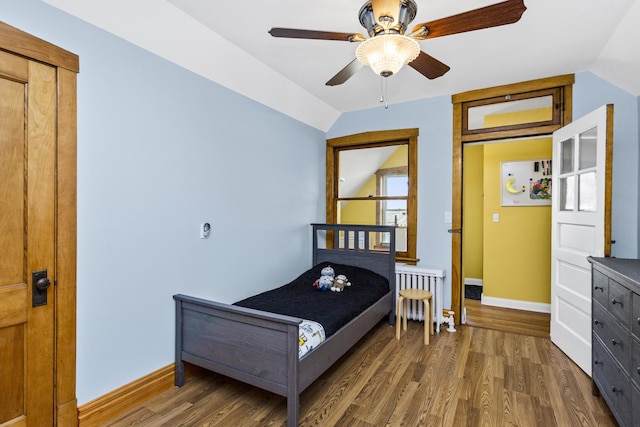 bedroom featuring dark wood-type flooring, ceiling fan, radiator heating unit, and vaulted ceiling