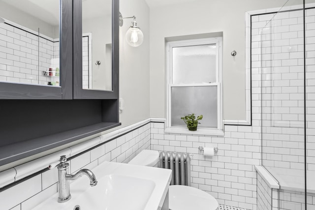 bathroom with tiled shower, toilet, sink, tile walls, and radiator