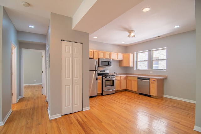 kitchen featuring stainless steel appliances, sink, light brown cabinetry, and light hardwood / wood-style floors