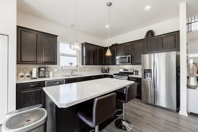 kitchen featuring a breakfast bar area, decorative light fixtures, appliances with stainless steel finishes, a kitchen island, and decorative backsplash