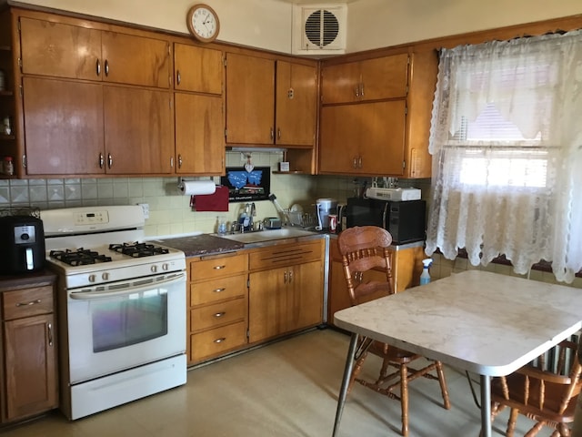 kitchen featuring tasteful backsplash, sink, and white range with gas stovetop