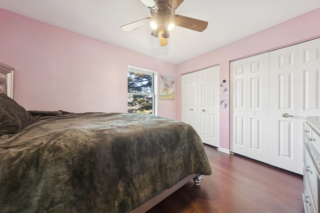 bedroom featuring dark hardwood / wood-style floors, two closets, and ceiling fan