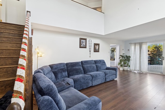 living room with a towering ceiling and dark hardwood / wood-style flooring