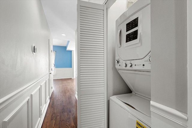 clothes washing area with dark hardwood / wood-style flooring and stacked washing maching and dryer