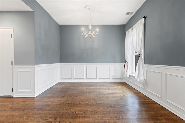 spare room featuring dark hardwood / wood-style floors and an inviting chandelier