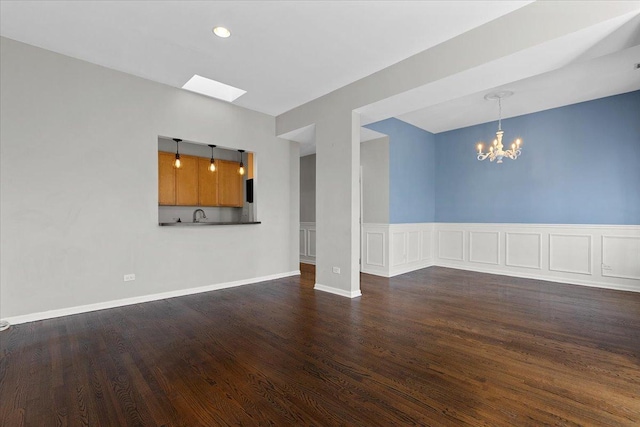 unfurnished living room with dark hardwood / wood-style floors, sink, and a notable chandelier