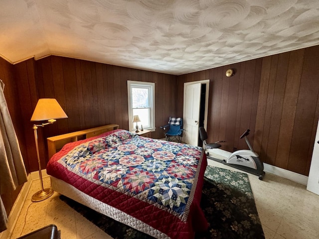 bedroom featuring a textured ceiling and wooden walls