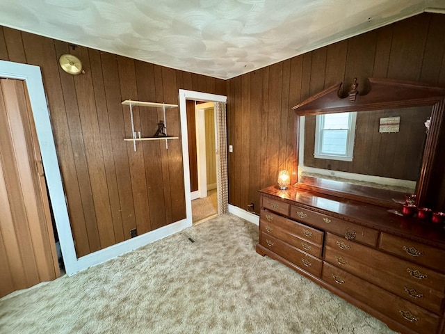 unfurnished bedroom with wooden walls and light colored carpet