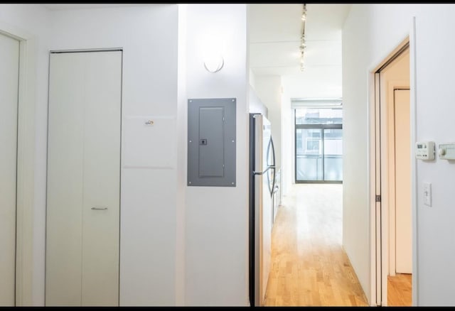 corridor with track lighting, electric panel, and light wood-type flooring