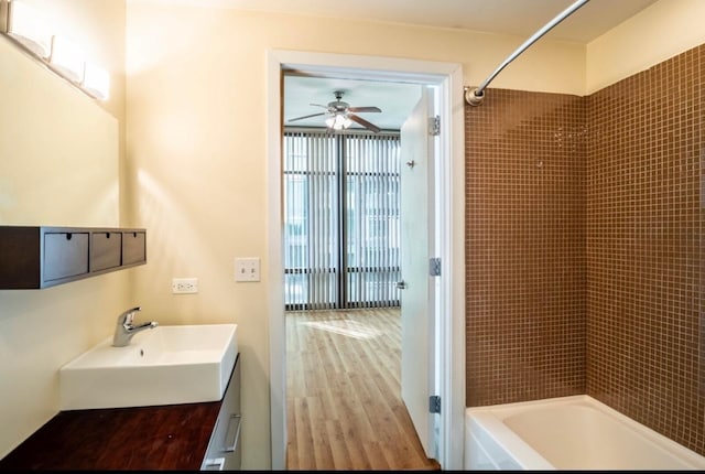 bathroom featuring vanity, tiled shower / bath combo, wood-type flooring, and ceiling fan