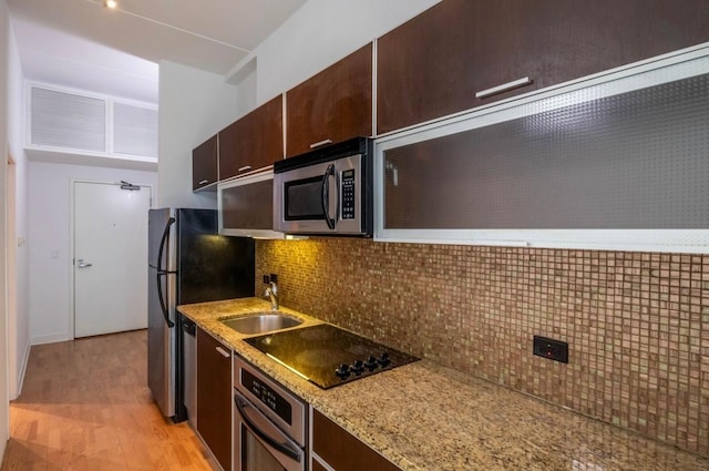 kitchen featuring sink, appliances with stainless steel finishes, dark brown cabinetry, decorative backsplash, and light wood-type flooring